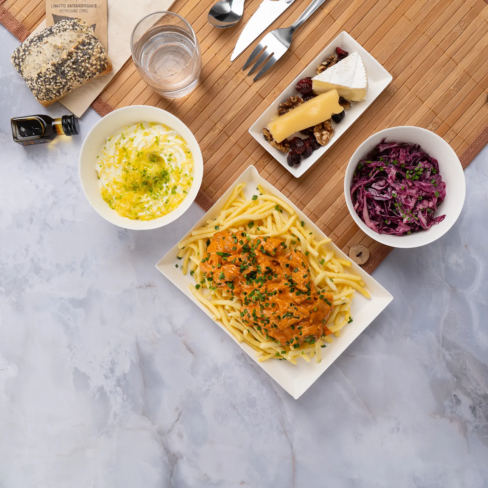 Plateau repas d'entreprise bœuf façon stroganoff et spaetzle, servi sur set bambou avec couverts inox — Les Jardins d'Épicure, traiteur à Paris et en Île-de-France