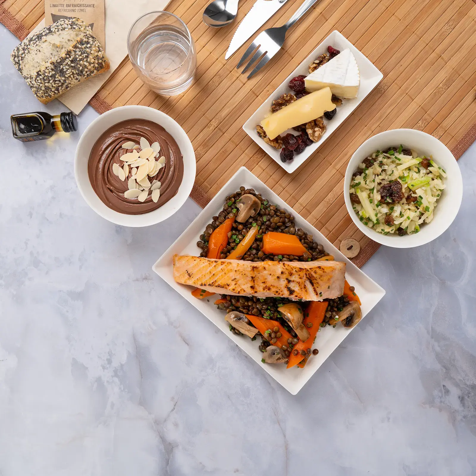 Plateau repas d'entreprise sans gluten pavé de saumon ASC et lentilles beluga, servi sur set bambou avec couverts inox — Les Jardins d'Épicure, traiteur à Paris et en Île-de-France